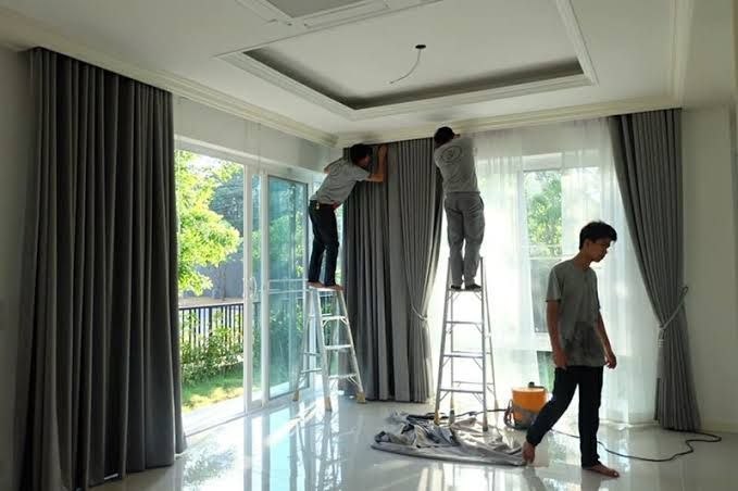ทีมช่างติดตั้งผ้าม่านสีเทาในบ้านพัก